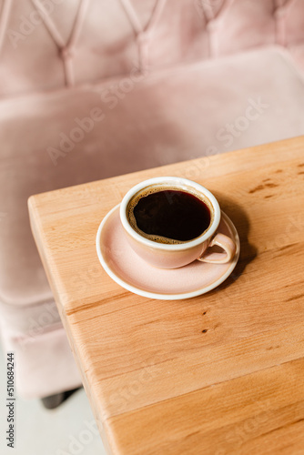 Black strong coffee in a pink cup on the coffee table. A stylish concept with space for text for your advertising. Roasting of coffee beans. Barista cooked Americano
