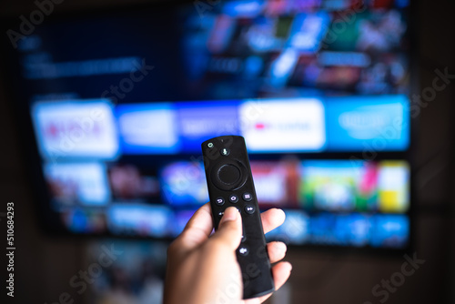 Rio de Janeiro / Brazil- February 3, 2021: amazon fire tv stick remote in hand with selective focus tv background. During the COVID-19 lockout.