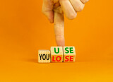 You use or lose it symbol. Concept words You use and You lose on wooden cubes. Businessman hand. Beautiful orange table orange background. Business and you use or lose it concept. Copy space.