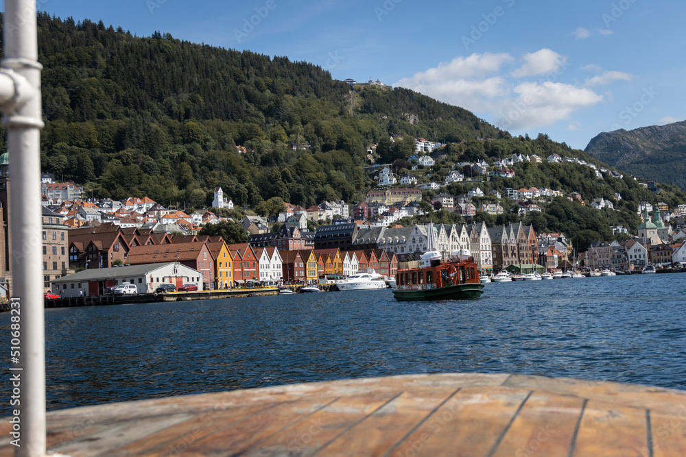 view of bryggen, a historical landmark in central Bergen in Norway, Scandinavia, from a tourist boat with another passenger boat on the waters. 