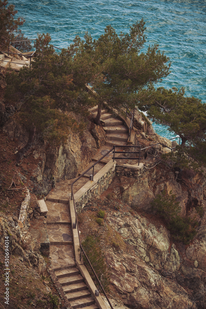 Marine motifs. Stone stairs in rock leading down to the sea. Ancient stone steps in the rock. Stairs to the sea. Nature, cliffs and coastline landscape.