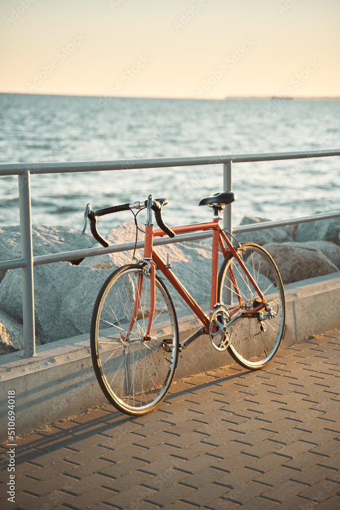 Fototapeta premium Orange vintage road bicycle. Closeup of a bike on the seaside during a summer evening. Old cycle restored.
