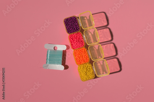 a palette of colored beads in a plastic box and a fishing line on a colored background
