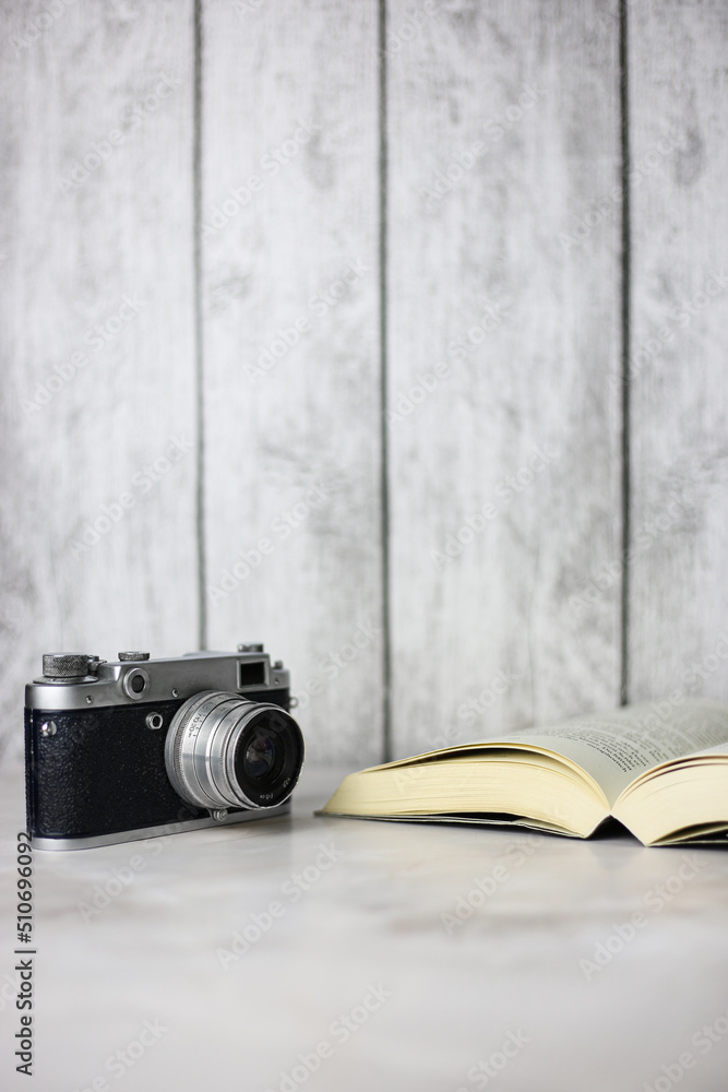 Vintage camera next to an open book on a light background