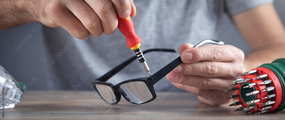 Optical technician repairing eyeglasses with screwdriver. Optical technician repairing eyeglasses with screwdriver.