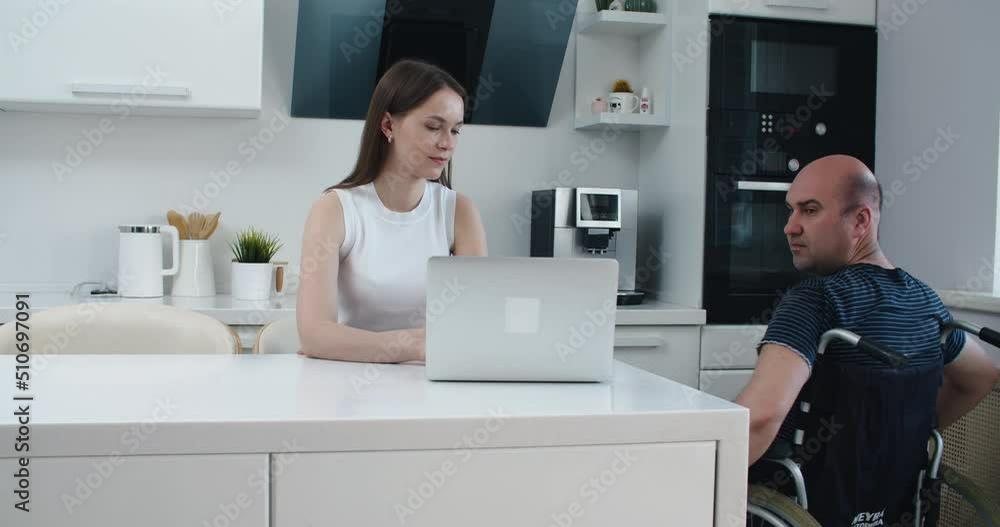 man in wheelchair and his wife using laptop at home. Help. High quality 4k footage man in wheelchair and his wife using laptop at home. Help. High quality 4k footage