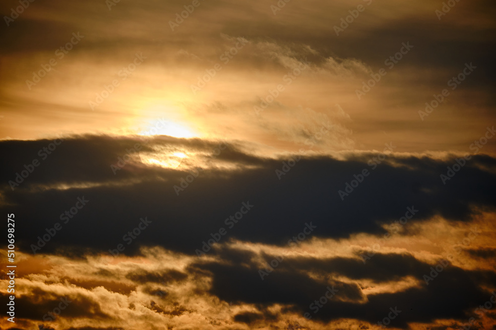 Evening dramatic sky with clouds during sunset. The sun sets behind dark clouds
