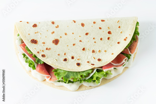 Italian street food flat lay with piadina isolated on a white background.  Piadina romagnola - Italian flatbread with prosciutto, salad and cream cheese