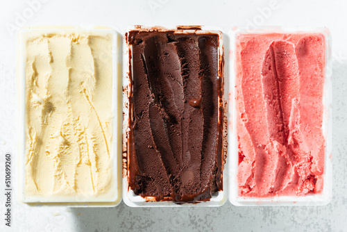 real Italian artisanal ice cream in packing box: chocolate, strawberries, vanilla with berries and a spoon photo