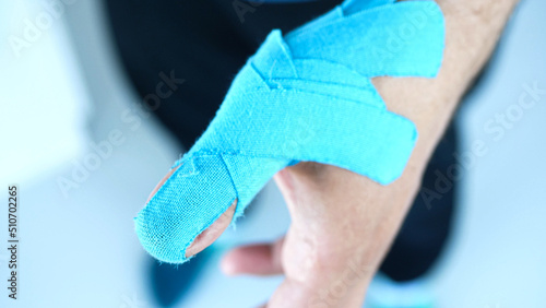 Foto Man showing kinesiology taping on his thumb
