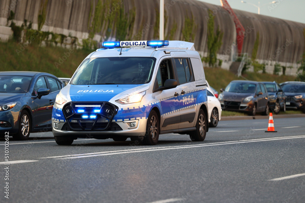 Radiowóz polskiej policji drogowej wieczorem w mieście podczas zabezpieczenia wypadku. - obrazy, fototapety, plakaty 