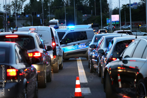 Radiowóz polskiej policji drogowej wieczorem w mieście podczas zabezpieczenia wypadku.
