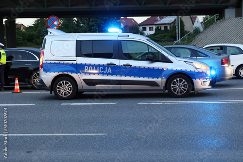 Radiowóz polskiej policji drogowej wieczorem w mieście podczas zabezpieczenia wypadku.