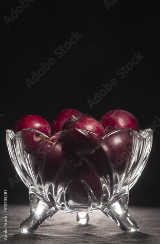 plums inside a glass container with black background