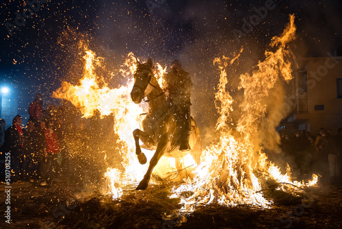 horses with their riders jumping bonfires as a tradition to purify animals.. photo