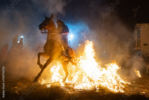 horses with their riders jumping bonfires as a tradition to purify animals..