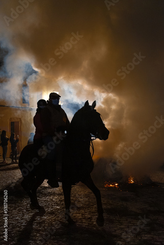 horses with their riders jumping bonfires as a tradition to purify animals..
