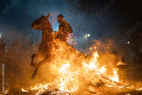horses with their riders jumping bonfires as a tradition to purify animals Fototapet