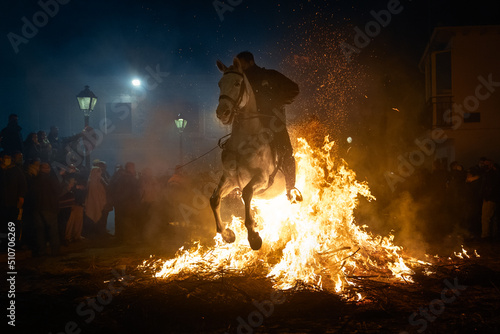 Fototapeta horses with their riders jumping bonfires as a tradition to purify animals