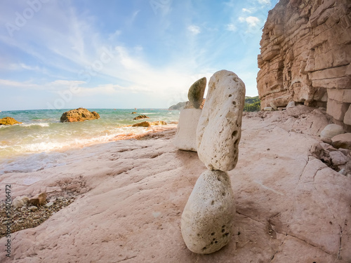 Pink stone balancing pyramid on the turquoise beach of Sassi Neri overlooking the Adriatic sea.Beautiful landscape overlooking the sea, perfect beach, azure water. Sirolo, Ancona, Marche photo
