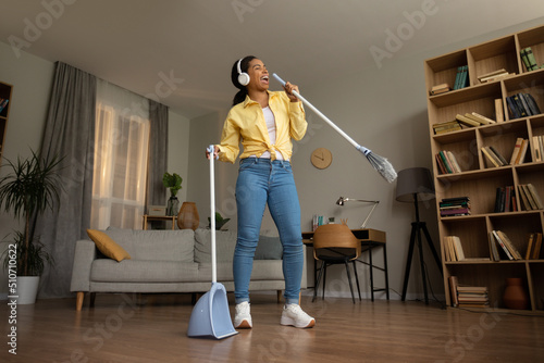 Happy African Female Having Fun Sweeping Floor Singing At Home