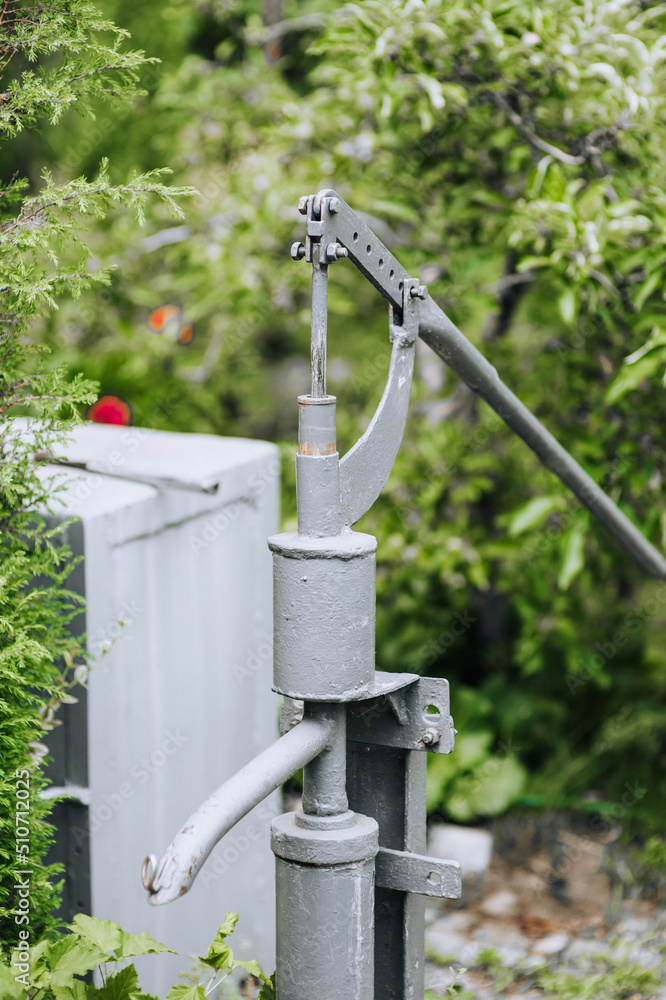 An old metal homemade well stands in a garden in nature. An old metal homemade well stands in a garden in nature.