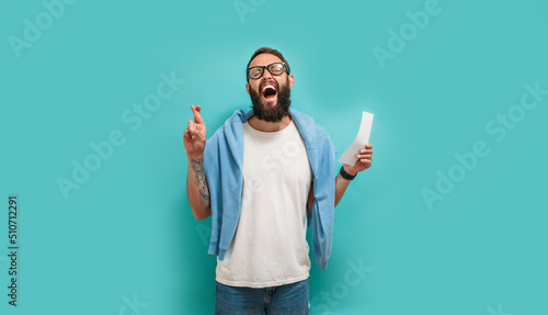Obraz na plátně Excited happy young male winner feeling joy winning lottery, placing bets, getting cashback online gift isolated on blue background