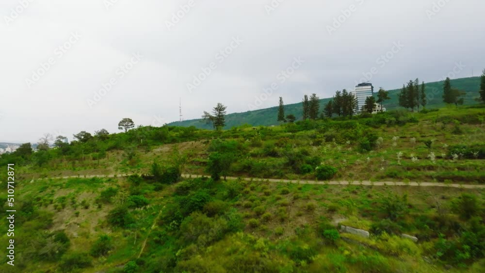 Aerial view of Tbilisi city, Georgia. Drone climbs green hill and flies up to reveal a magnificent view of beautiful city of Tbilisi Aerial view of Tbilisi city, Georgia. Drone climbs green hill and flies up to reveal a magnificent view of beautiful city of Tbilisi