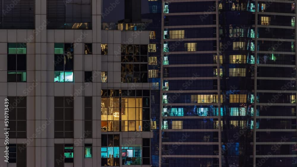 Apartment panoramic windows of a glazed skyscraper glow at night with city lights reflection aerial timelapse. Illuminated towers Apartment panoramic windows of a glazed skyscraper glow at night with city lights reflection aerial timelapse. Illuminated towers
