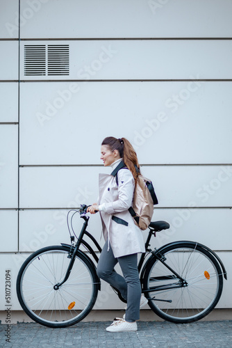 smiling elegant woman in beige trench coat outside in city