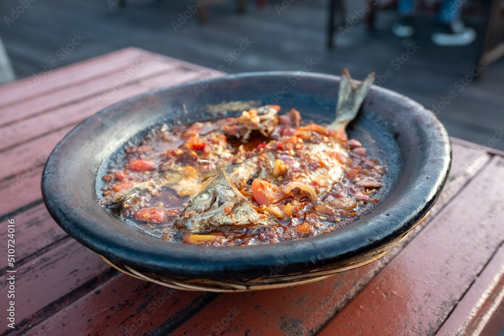 processed chili sauce made from tomatoes and chilies cooked with fresh fish on a clay plate, a typical food from Indonesia, Bontang, East Kalimantan, in Indonesian this food is called processed chili sauce made from tomatoes and chilies cooked with fresh fish on a clay plate, a typical food from Indonesia, Bontang, East Kalimantan, in Indonesian this food is called