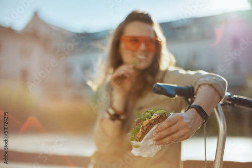 Smiling woman and overall eating while sitting outside in city