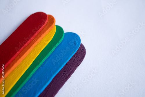 detalle de batelenguas de madera multicolor, con bandera de orgullo gay, sobre fondo blanco, pintado con pintura acrílica photo