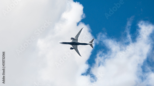 Passenger airplane flying overhead. Modern airliner taking off and landing background with copy space. Blue sky and white clouds