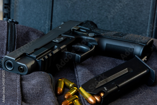 Artistic photo of a semi automatic 9mm handgun on a black background in a tactical military setting with a loaded magazine and loose rounds of ammunition photo