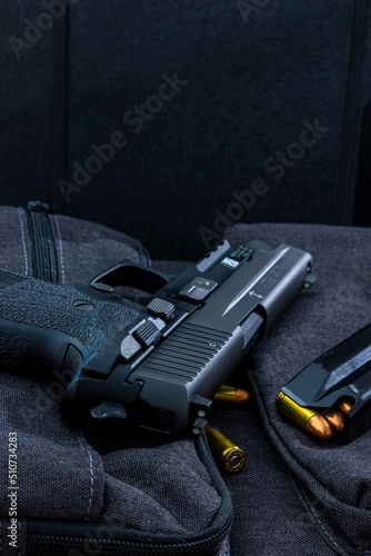 Artistic photo of a semi automatic 9mm handgun on a black background in a tactical military setting with a loaded magazine and loose rounds of ammunition photo