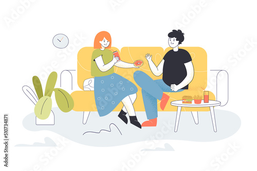 Couple sitting on sofa in living room  eating fast food together. Young woman giving donut to hungry man flat vector illustration. Love  lunch concept for banner  website design or landing web page