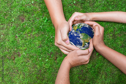 Fototapeta Naklejka Na Ścianę i Meble -  Environment conservation concept. Young children hands holding globe on green nature background for sustainable development goal.  world image by NASA
