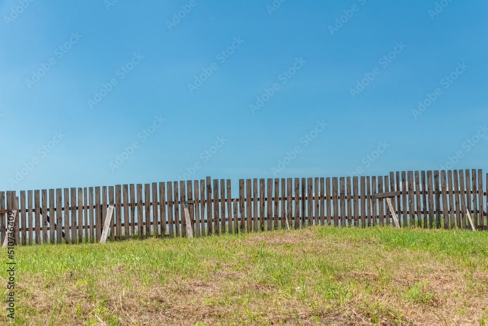 crooked wooden fence on a farm against the sky