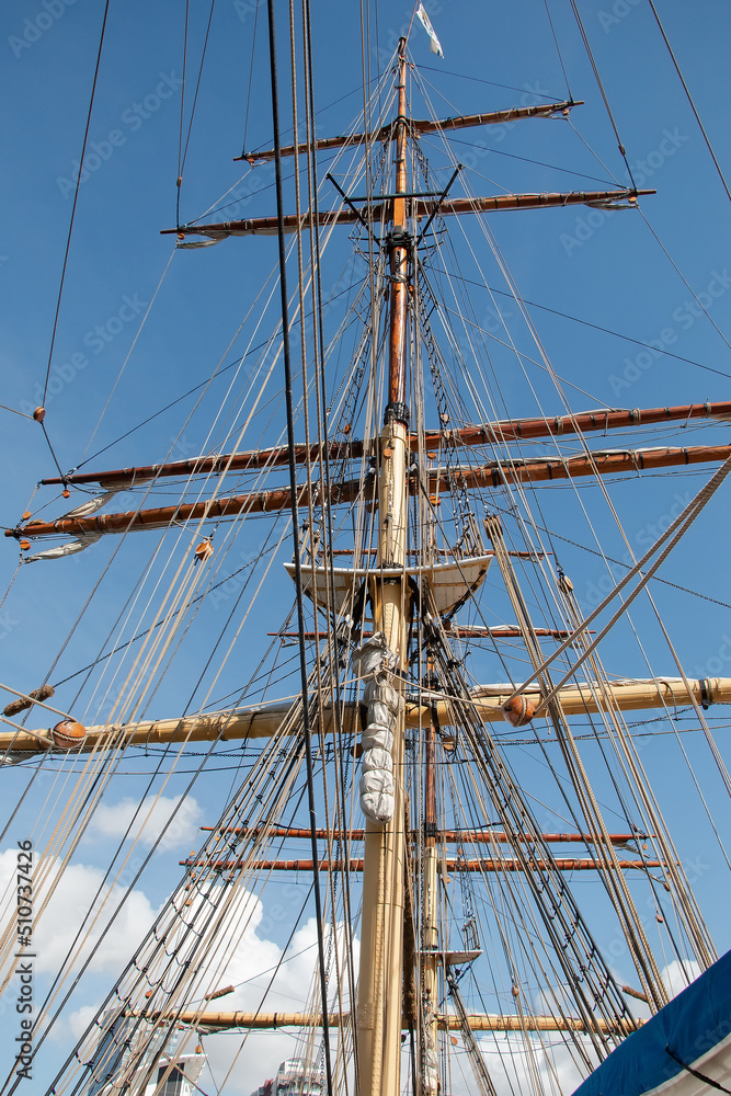 Ropes and the mast to control the sails, details of the device of the yacht, sailing ship equipment against the blue sky, vertical view Ropes and the mast to control the sails, details of the device of the yacht, sailing ship equipment against the blue sky, vertical view
