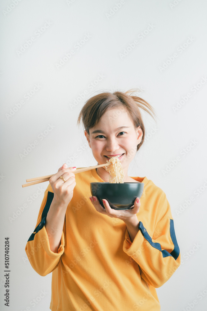 Asian girl holding a bowl of noodles with chopsticks and eating it, isolated on white background Asian girl holding a bowl of noodles with chopsticks and eating it, isolated on white background