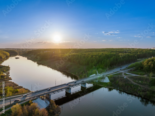 Beautiful view of the bridge across the Iset river in the city of Kamensk-Uralsky at sunset in spring. Kamensk-Uralskiy, Sverdlovsk region, Ural mountains, Russia.