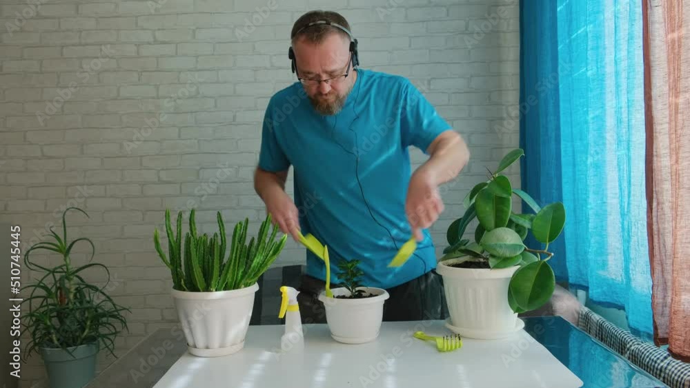Funny adult man happily taking care of indoor plants. Happy home lifestyle. Man doing a hobby and having fun. Funny adult man happily taking care of indoor plants. Happy home lifestyle. Man doing a hobby and having fun.