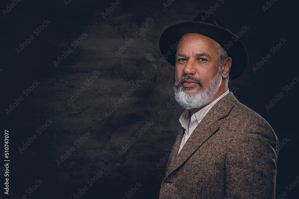 Portrait of happy old man dressed in suit and hat posing against dark background. Portrait of happy old man dressed in suit and hat posing against dark background.