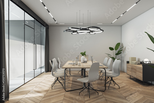 Side view on sunlit meeting room interior design with stylish lamp above light wooden conference table with vases and laptops, chairs on parquet floor, grey walls and glass door. 3D rendering