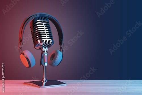 Podcasting and radio concept with retro microphone and headphones on empty wooden table and dark blank wall background with place for your logo or text. 3D rendering, mock up photo