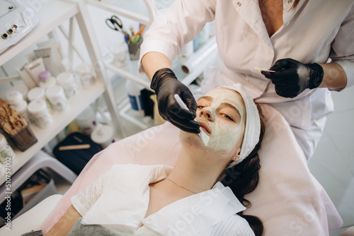 Applying facial mask at woman face at beauty salon