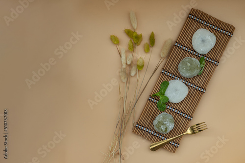 Green tea and Red bean daifuku serve with brass fork on bamboo placemat with orange background. Japanese tradiitonal snack, Copy space, Top view, Selective focus. photo