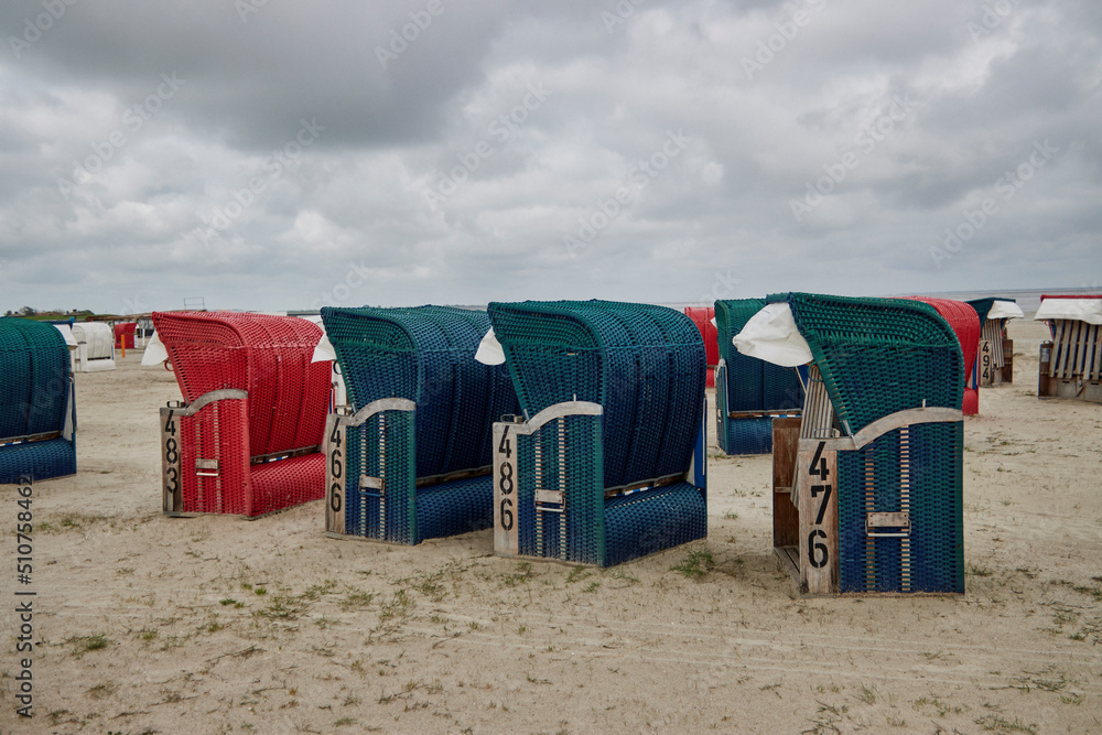 Obraz premium Verlassene Strandkörbe im niedersächsichen Bensersiel bei schlechtem Wetter