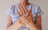 an elderly woman suffering from pain in her hand rubs her wrist, close-up